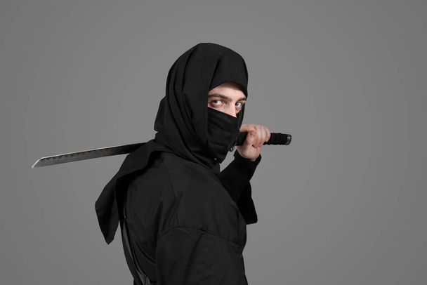 Férfi ninja karddal szürke háttér - Fotó, kép