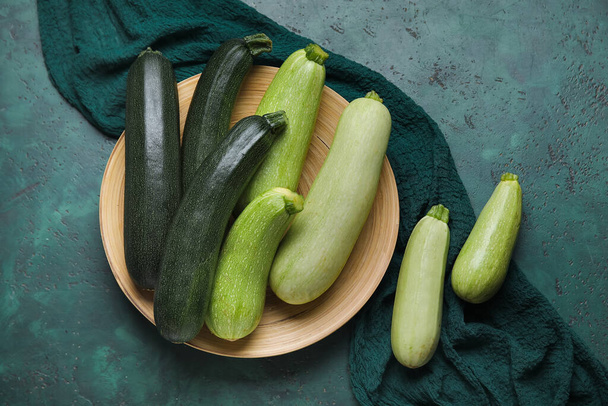 Plate with fresh zucchini on green background - Фото, зображення
