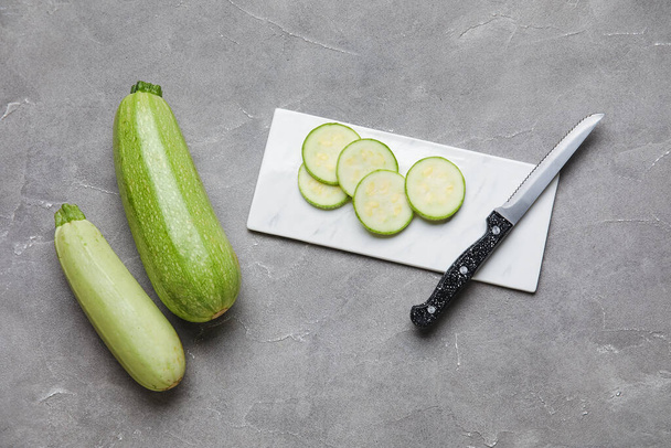 Tavola con taglio e zucchine intere su fondo grigio - Foto, immagini