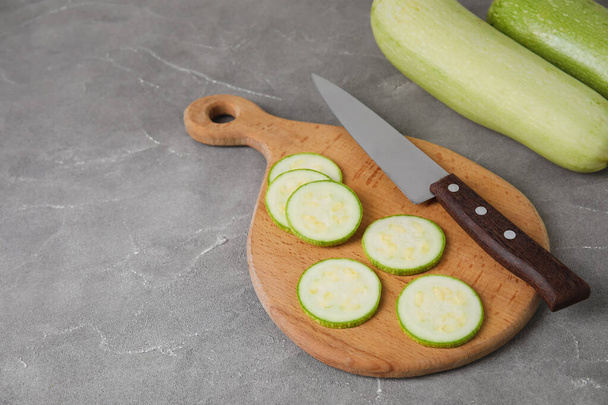 Wooden board with slices of fresh zucchini on grey background - Fotó, kép