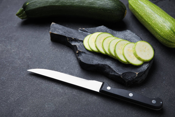 Board with slices of fresh green zucchini on black background - Foto, afbeelding