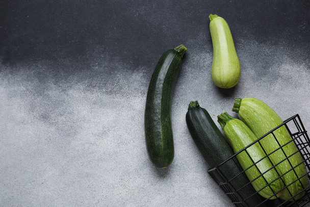 Korb mit frischen grünen Zucchini auf grauem Hintergrund - Foto, Bild