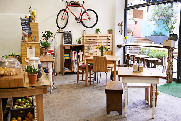 Puste, kawiarnia i przestrzeń wewnętrzna ze stołem, krzesłami i meblami lub małym biznesem, bistro i kawiarnia o niepowtarzalnym designie i stylu. Tło, kreatywne startup i sklep spożywczy z rowerem na ścianie. - Zdjęcie, obraz