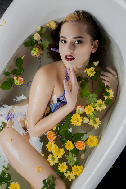 Vista superior de una mujer sexy en lencería en un baño con flores y pétalos. - Foto, Imagen