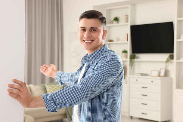 Handsome man inviting to come in room at home - Photo, image