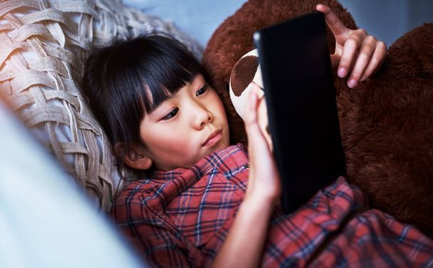 Aplicaciones que entretienen durante horas. una niña usando una tableta digital en casa - Foto, Imagen