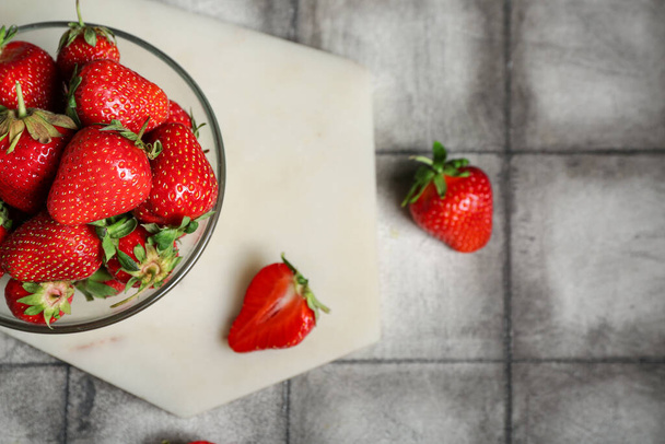 Bowl with fresh strawberries on grey tile background - Photo, Image