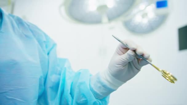 медсестра в стерильной перчатке вручает ножницы хирургических инструментов хирургу во время операции в больнице - Кадры, видео
