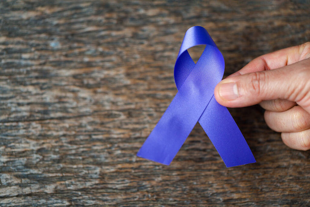 Purple ribbon for the awareness about the unacceptability of the violence against women on dark gray rustic wooden surface. Top view with space for text. Domestic violence awareness. - Φωτογραφία, εικόνα
