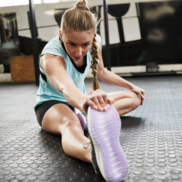 Nyújtás, bemelegítés és nő a tornateremben edzésre, edzésre és edzésre a padlón. Egészség, sport és női személy nyújtózkodó lábak a sportközpontban wellness, teljesítmény és rugalmasság érdekében. - Fotó, kép