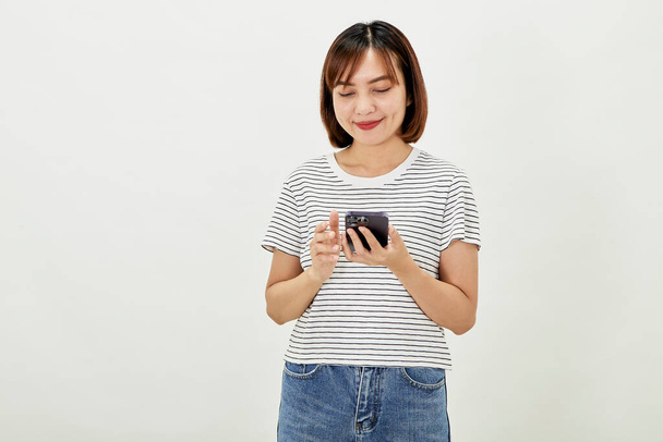Sorrindo mulher asiática usando um smartphone, de pé contra mensagens de texto em um telefone celular em fundo branco, pessoas e conceito de tecnologia - Foto, Imagem