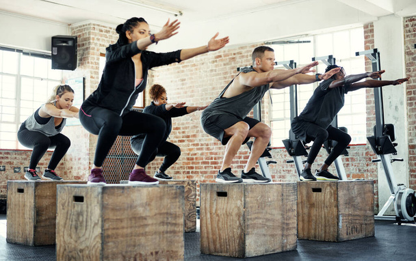 Todo sobre esa aptitud. un grupo enfocado de jóvenes saltando a las cajas como ejercicio dentro de un gimnasio - Foto, imagen