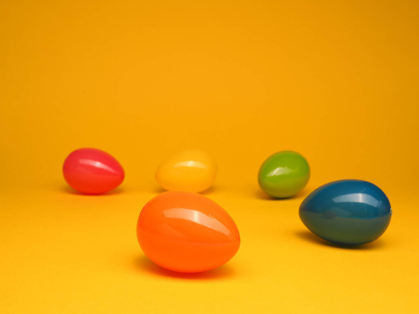 Colorful plastic Easter eggs on a yellow studio background, Happy Easter concept backdrop - Photo, Image