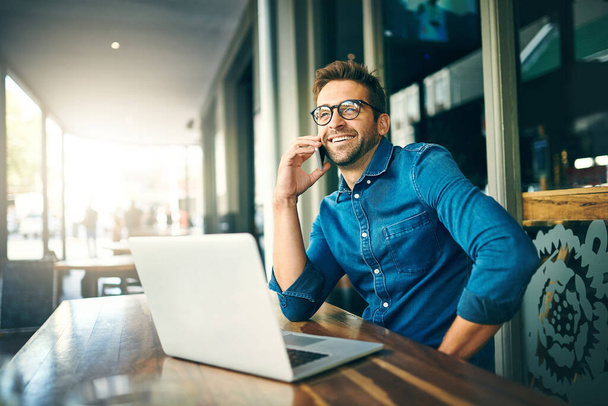 Добро пожаловать в цифровую эпоху. красивый молодой бизнесмен, сидящий один и разговаривающий по телефону в кафе - Фото, изображение