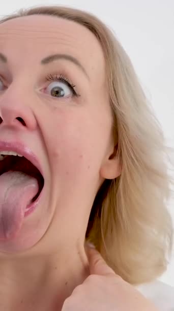白い背景の上で笑う非常に長い舌の女性は、医師の喉の不満がそれを行うにはしたくないことを示しています外では、不服従の兆候として舌を突き出し抗議  - 映像、動画