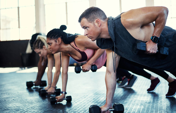 El trabajo duro siempre vale la pena. un grupo de fitness usando pesas en su sesión en el gimnasio - Foto, imagen