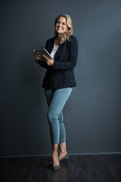 So laufe ich einen organisierten Tag. Studioporträt einer reifen Geschäftsfrau mit einem digitalen Tablet vor grauem Hintergrund - Foto, Bild