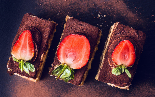 Chocolate  tiramisu cake with strawberries on black slate, top view - Foto, afbeelding