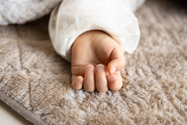 Halıda uyuyan Asyalı bir bebeğin sol eli. Yüksek kalite fotoğraf. 02.25.2023. Bu bir yıllık bir çocuk eli.. - Fotoğraf, Görsel