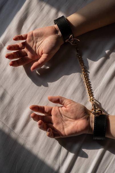 Close-up of womans hands in leather handcuffs. Sex toy - Fotografie, Obrázek