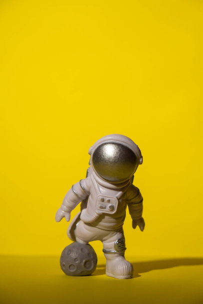 astronauta juguete plástico sobre fondo amarillo de colores Copiar el espacio. Concepto de viajes fuera de la tierra, vuelos comerciales de astronautas privados. Misiones espaciales y sostenibilidad - Foto, Imagen