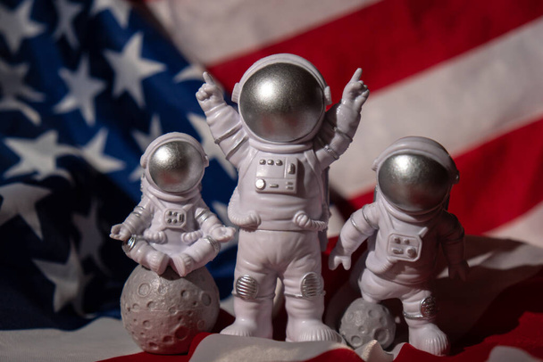 アメリカの国旗を背景に宇宙飛行士をフィギュア3体コピースペース。地球旅行、民間宇宙飛行士の商業便のうちの月の概念に米国着陸の50周年。スペース - 写真・画像