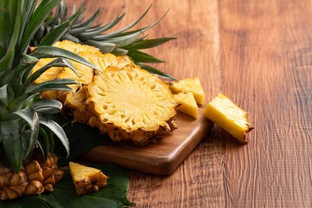Close up of fresh cut pineapple on a tray over dark wooden table background. - Foto, Bild