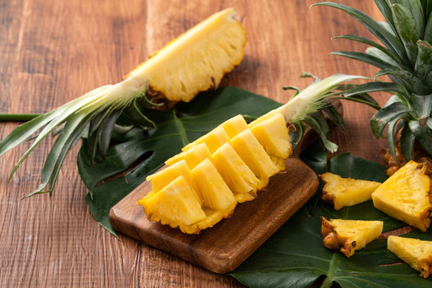 Close up of fresh cut pineapple on a tray over dark wooden table background. - Foto, Bild