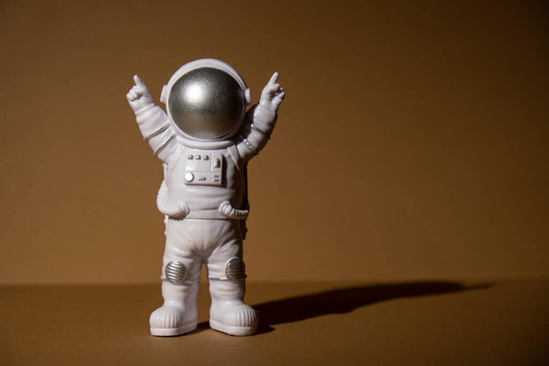 Plastic toy figure astronaut on beige neutral background Copy space. Concept of out of earth travel, private spaceman commercial flights. Space missions and Sustainability - 写真・画像