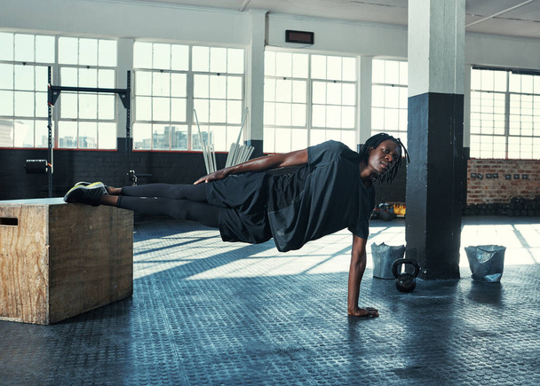 Planking zihin ve beden içindir. Genç bir adam spor salonunda ahşap bir blokla yan tahtayı yapıyor. - Fotoğraf, Görsel
