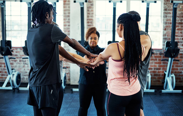 Hands together. a focused young group of people forming a huddle together while one looks into the camera before a workout in a gym - Foto, imagen