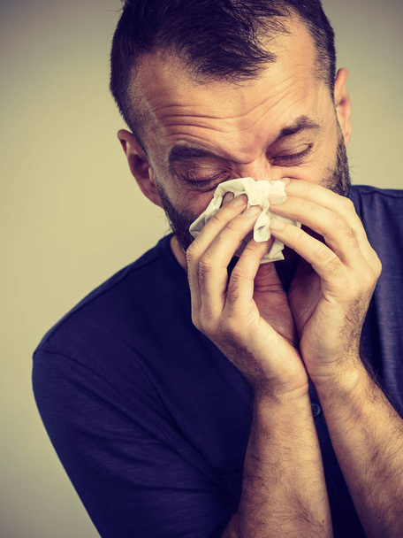 Man having flu, sneezing into hygienic tissue. Guy being sick, allergic blowing his nose. - Fotoğraf, Görsel