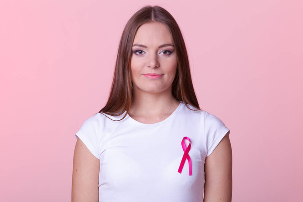 Woman wih pink cancer ribbon on chest. Healthcare, medicine and breast cancer awareness concept. Studio shot, pink light red background - Fotografie, Obrázek