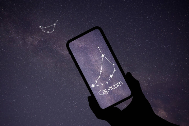 Man using stargazing app on his phone at night, closeup. Identified stick figure pattern of Capricornus (Capricorn) constellation on device screen - Photo, Image