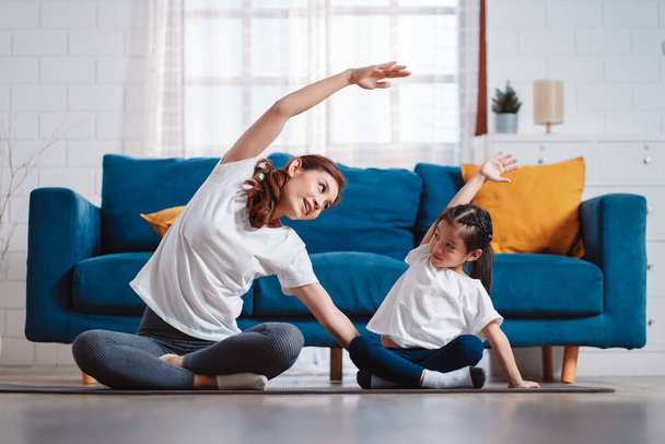 Matka a dcera spolu šťastně cvičí doma. pro flexibilitu budování svalové síly, sportovní trénink trénink rodina dohromady koncept. - Fotografie, Obrázek