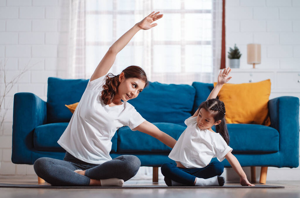 母親と娘が家で楽しく一緒に運動する。柔軟性のために筋肉の強さを構築します。. - 写真・画像