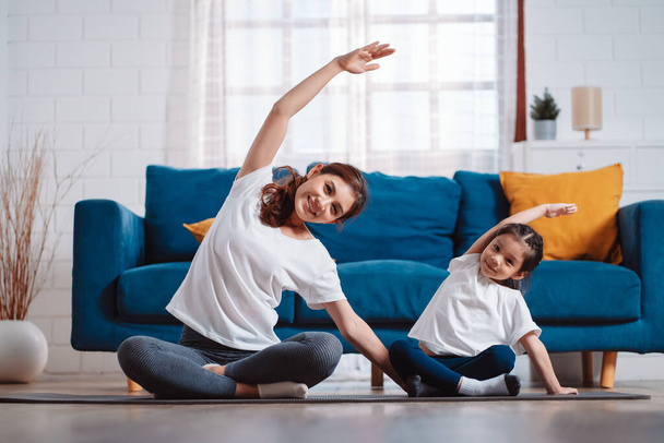 Mother and daughter exercising together happily at home. for flexibility build muscle strength, Sport workout training family together concept. - Фото, изображение