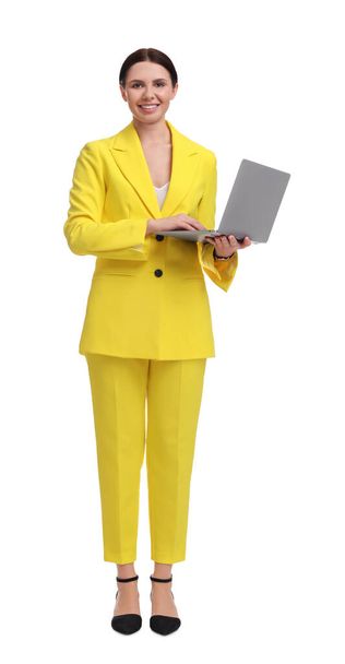 Beautiful businesswoman in yellow suit with laptop on white background - 写真・画像