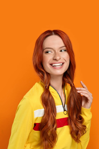 Portrait of smiling beautiful woman on orange background - Foto, imagen