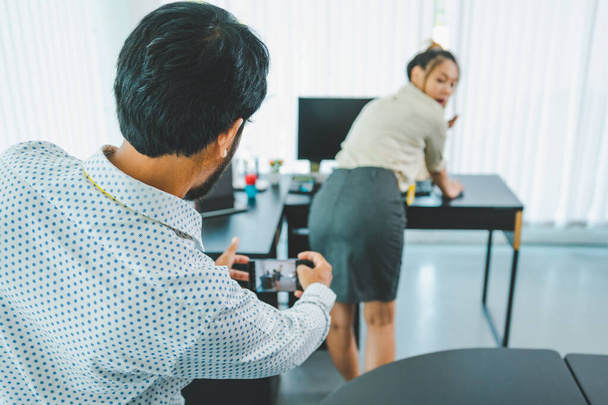 boss or supervisor is secretly using a mobile phone to film the buttocks of a female employee at work. Causing young employees to resist because they are uncomfortable and afraid of being sexually harassed There is sexual harassment in the workplace. - Photo, Image