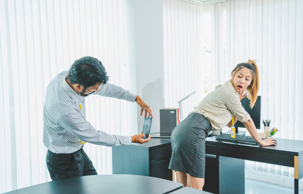 boss or supervisor is secretly using a mobile phone to film the buttocks of a female employee at work. Causing young employees to resist because they are uncomfortable and afraid of being sexually harassed There is sexual harassment in the workplace. - Foto, imagen