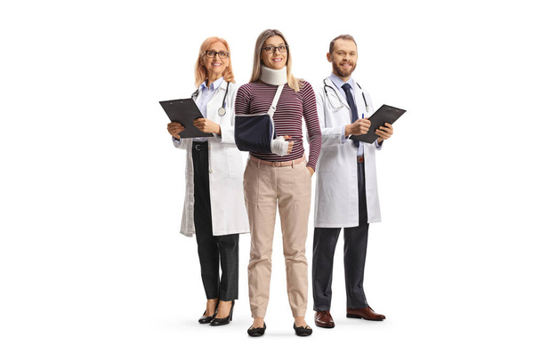 Young woman with a neck and arm injury standing with a male and female doctor isolated on white background - Photo, Image