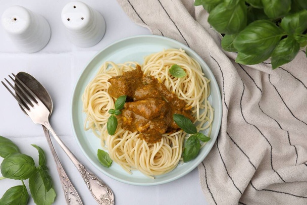 Delicious pasta and chicken with curry sauce served on white tiled table, flat lay - Foto, afbeelding