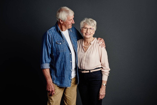 Non lascerò mai il tuo fianco. Studio ritratto di una coppia anziana affettuosa posa su uno sfondo grigio - Foto, immagini