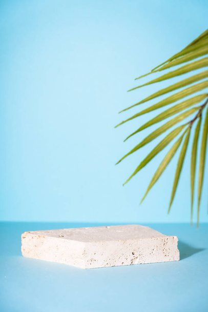 Stone podium for presentation cosmetic products on blue background with palm leaves. - Zdjęcie, obraz