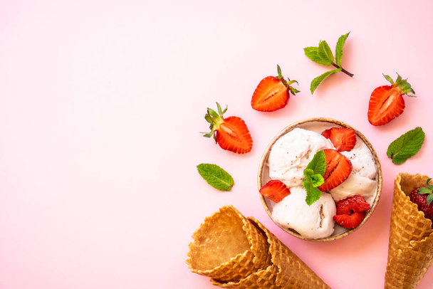 Homemade ice cream with fresh strawberries on pink background. Flat lay. - 写真・画像