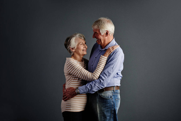 Non ti lascerò mai andare. Studio foto di una coppia anziana affettuosa posa su uno sfondo grigio - Foto, immagini
