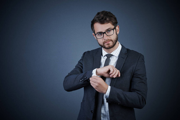 Youve gotta look your best. Studio portrait of a handsome young businessman adjusting his cuffs against a dark background - Photo, image