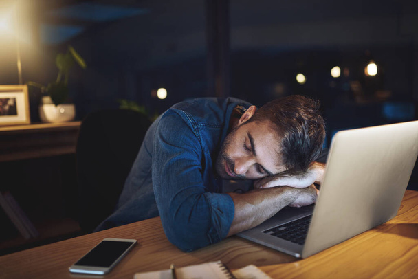 Jestem taka wyczerpana. przystojny młody biznesmen śpiący przy jego biurku podczas pracy do późna w nocy w nowoczesnym biurze - Zdjęcie, obraz