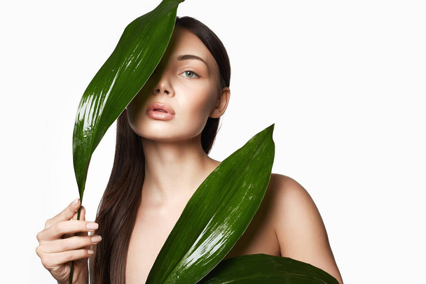 красивая девушка с пальмовыми листьями. Красивая молодая женщина с макияжем. Портрет красавицы. Естественная косметика - Фото, изображение